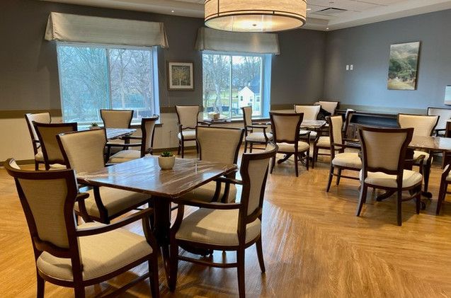 Interior view of Bright Side Manor senior living community featuring dining room with wooden furniture.