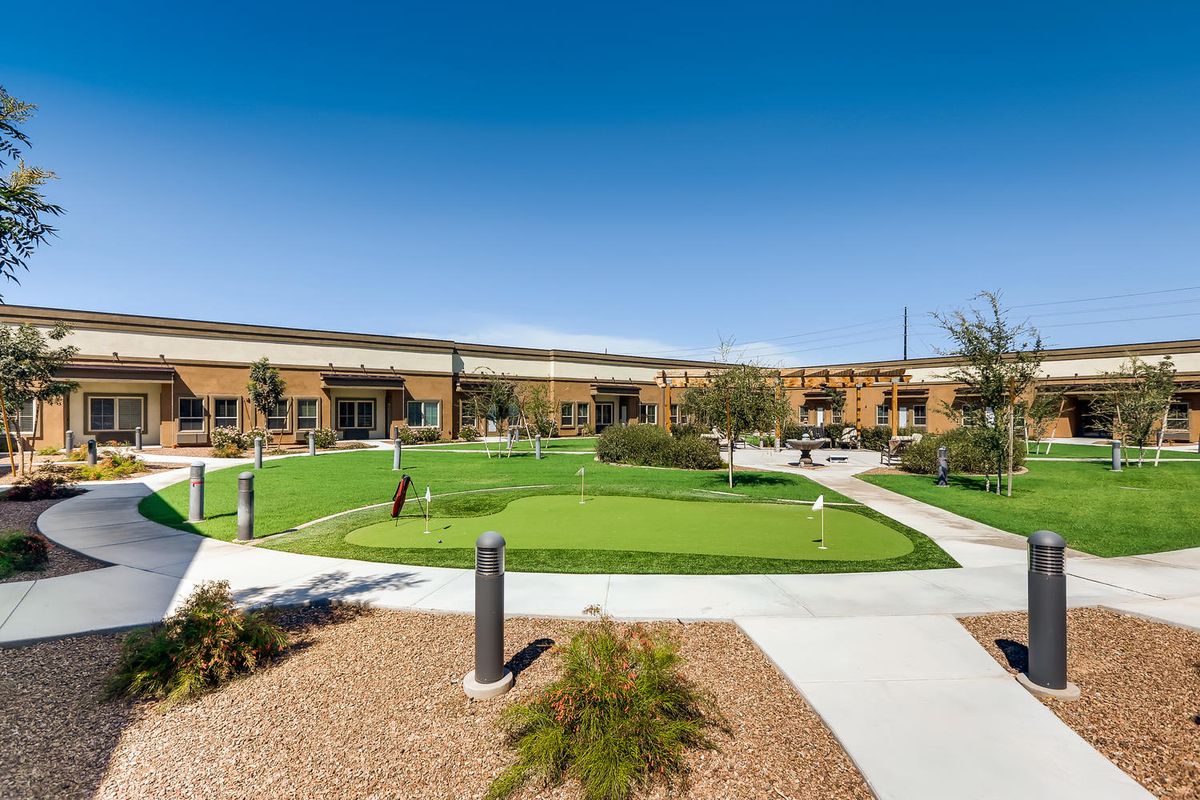 Senior living community, Mariposa Point At Algodon Center, with lush lawns, modern architecture, and outdoor seating.