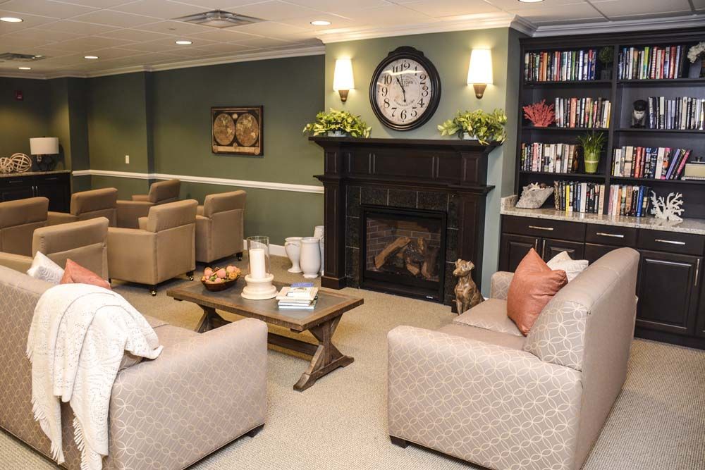 Senior enjoying cozy living room with stylish furniture and fireplace at The Chelsea At Warren.