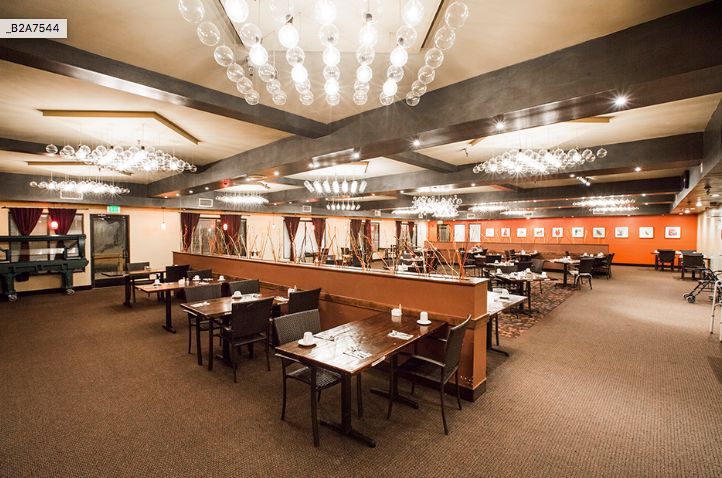 Indoor cafeteria at Vista Del Mar Senior Living with dining tables, chairs, and chandelier.