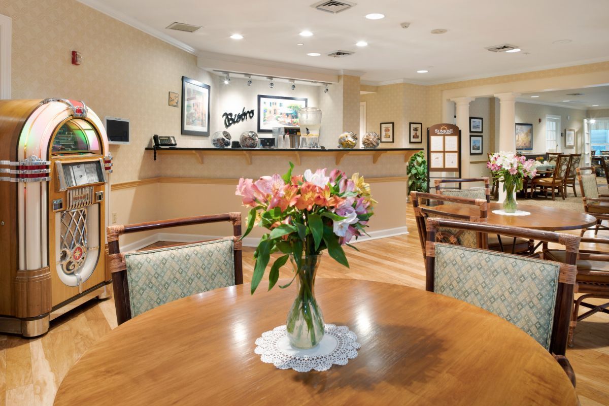 Interior view of Sunrise of Morris Plains senior living community featuring dining room and floral decor.