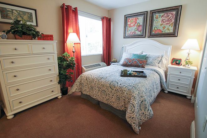 Senior living room at Brookdale Port Charlotte with bed, dresser, lamp, and home decor.