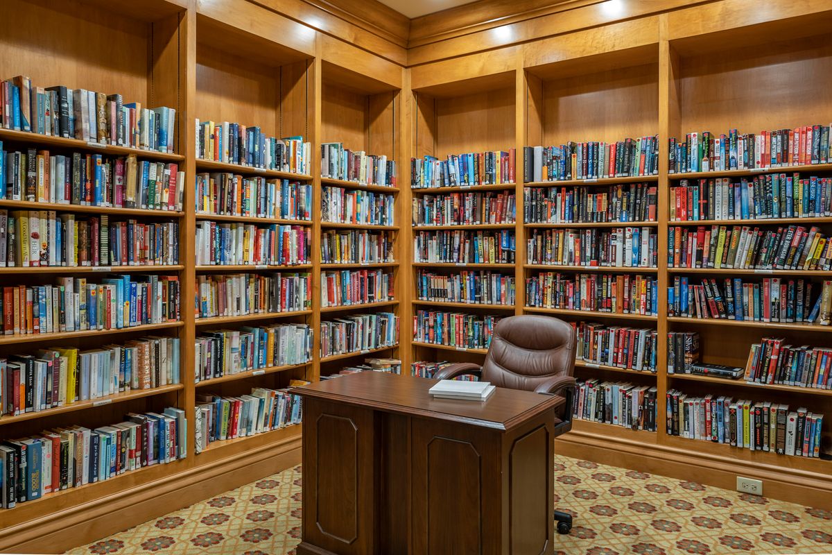 Senior living community library at Brookdale Lake Shore Drive with bookcases, desks, and chairs.