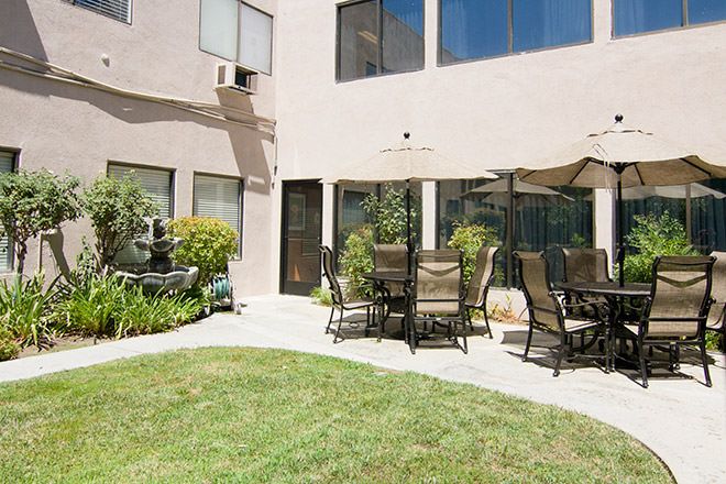 Summit Assisted Living of Tarzana featuring patio dining, lush lawns, and modern architecture.