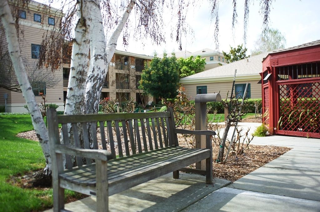 Senior living community, The Terraces of Los Gatos, featuring park benches, lush gardens, and modern architecture.