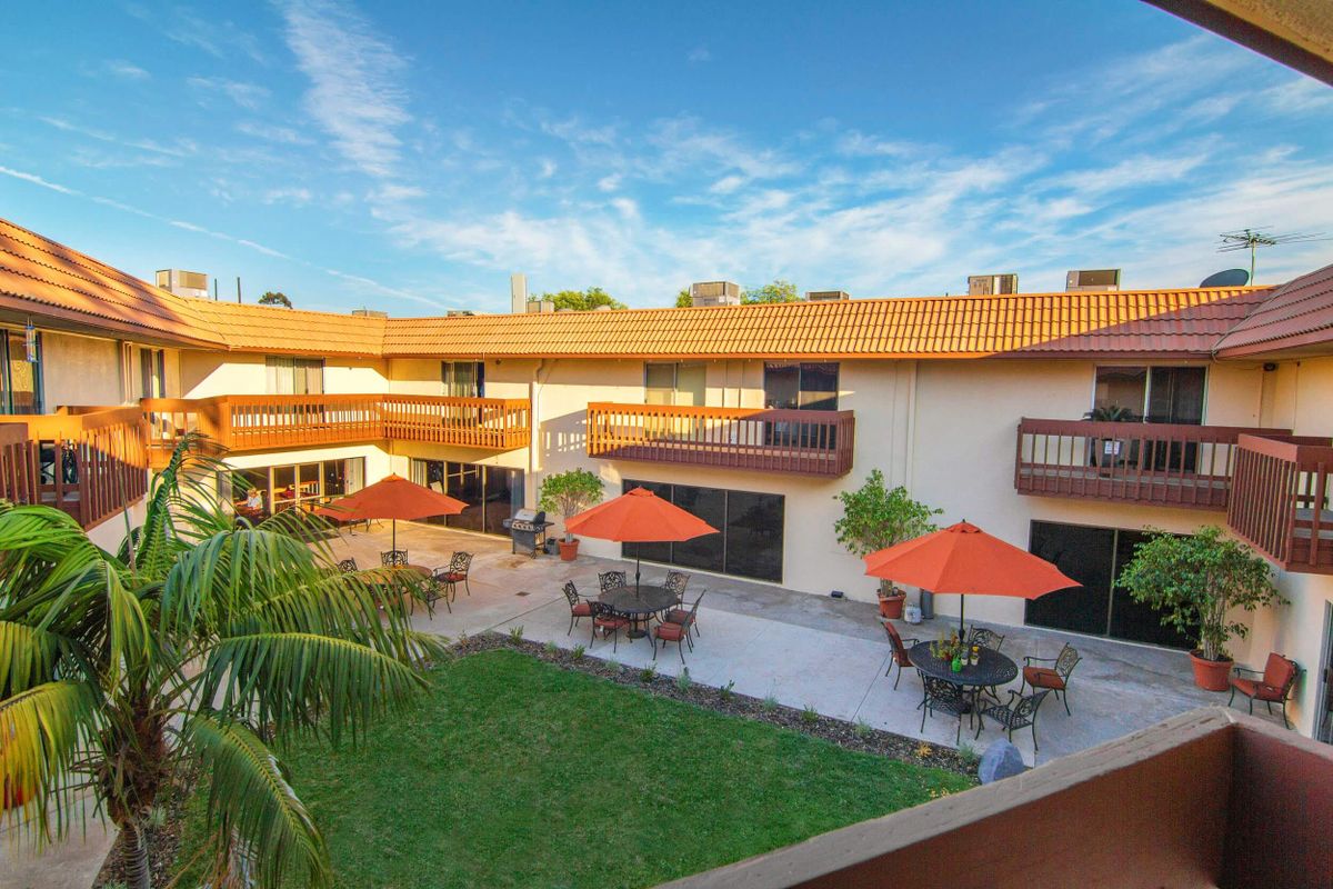 Senior living community, Palmcrest Grand Residence, featuring resort-style villa and lush plants.