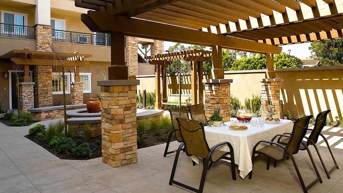 Senior living community Atria Golden Creek featuring patio dining, interior design, and backyard pergola.