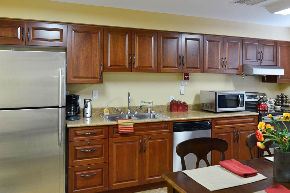 Interior view of Villa Manor Care Center's kitchen featuring modern appliances and wooden furniture.
