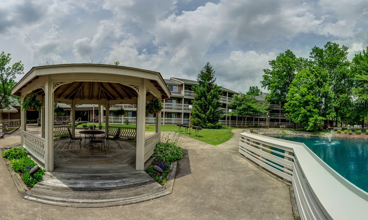 Seniors enjoy the outdoors at the Lodge Retirement Community, featuring a garden, pool, and scenic walkways.