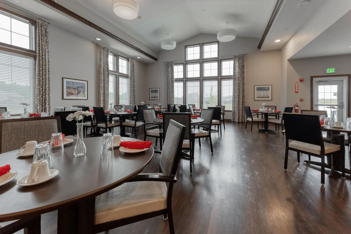 Interior view of Cedarhurst of Blue Springs senior living community's dining area with wooden furniture.