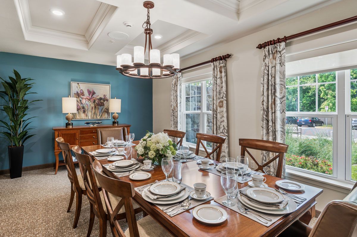 Architectural view of Wilshire Estates Retirement Living with furnished dining room, chandelier, and decor.