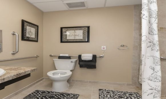 Senior living community interior at Simpson Place, featuring home decor in bathroom corner with toilet and photo frame.