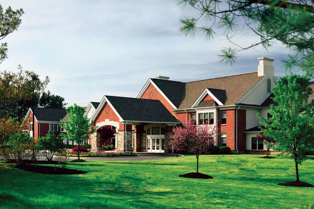 Grassy lawns and plant-filled outdoors of Brandywine Living at Moorestown Estates senior housing.
