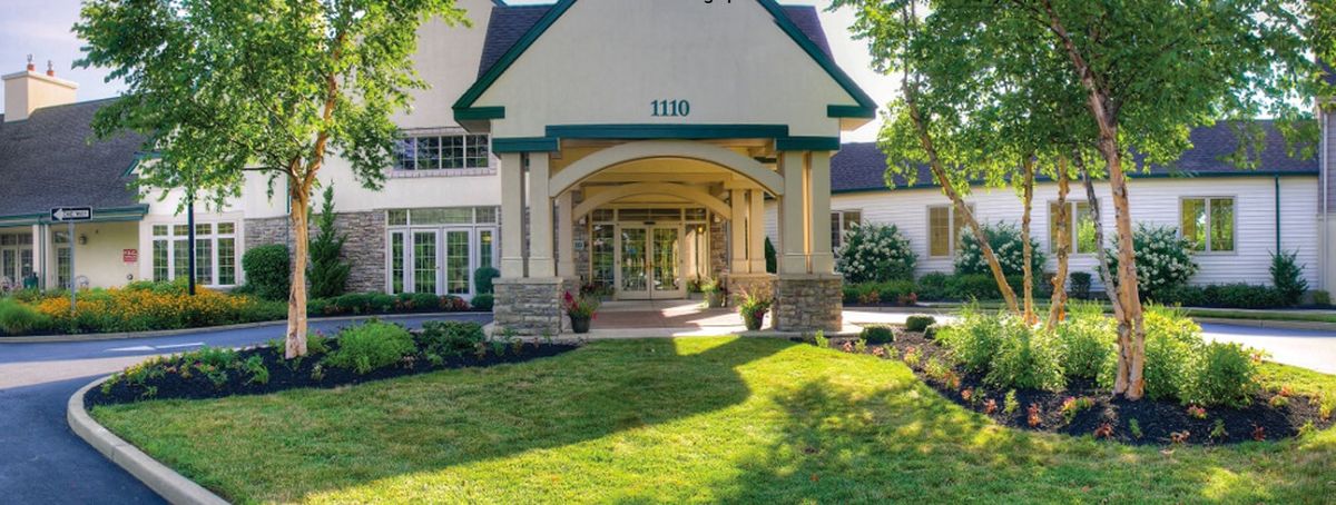 Senior living community, Lions Gate, featuring lush greenery, architectural buildings, and residents outdoors.