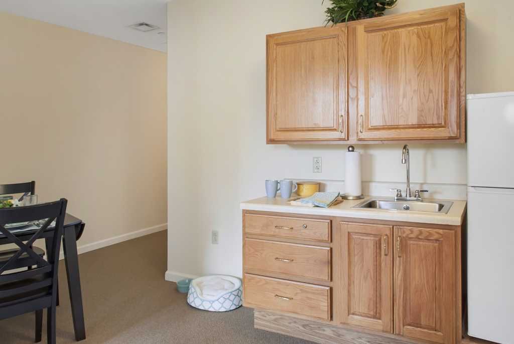 Interior view of Fairmont Senior Living on Clayton featuring a well-designed kitchen with wooden furniture.