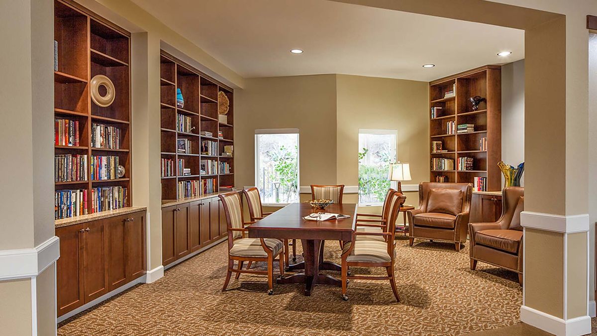 Interior view of Atria Walnut Creek senior living community featuring dining room with wooden furniture.