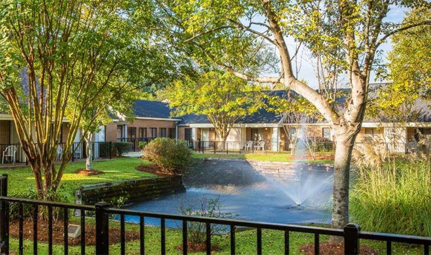 Senior living community, Stiles Apartments, featuring lush gardens, a pond, and modern architecture.