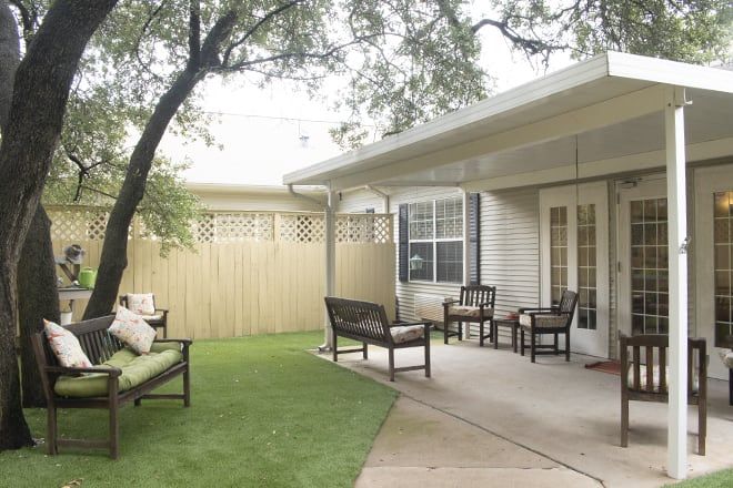 Senior enjoying outdoors at Brookdale North Austin with lush lawn, patio furniture, and pergola.