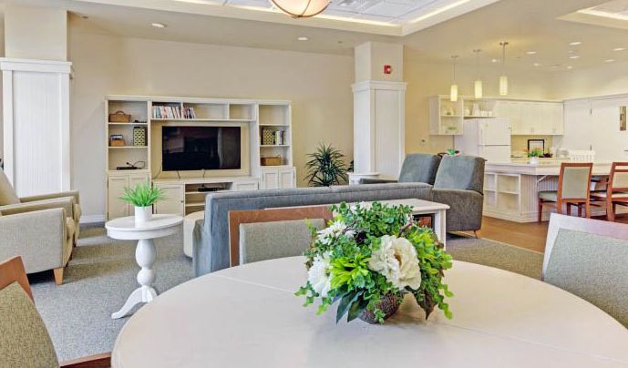 Senior living room at Merrill Gardens At Lafayette with modern decor, dining area, and electronics.