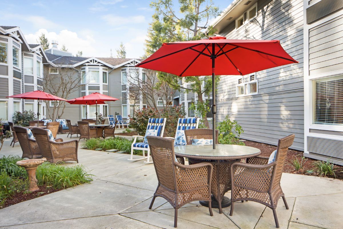 Senior living community Ivy Park at Walnut Creek featuring patio dining area and lush greenery.