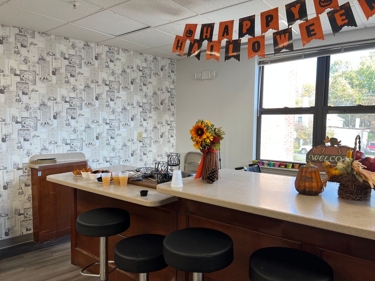 Interior view of Clara Barton Assisted Living Community with residents, floral decor, and dining area.