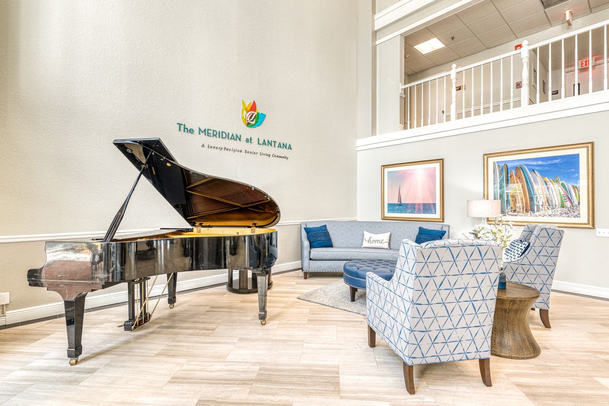 Interior view of The Meridian At Lantana senior living community featuring grand piano and art.