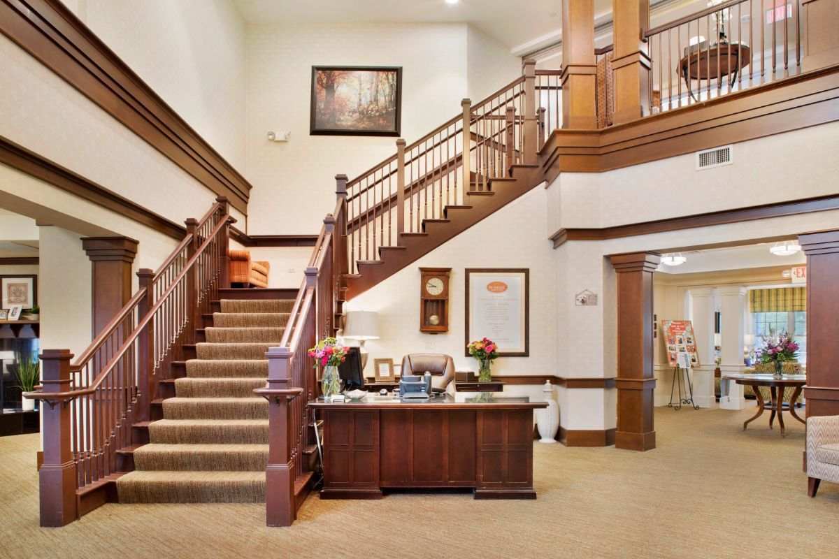 Senior living community interior at Sunrise at Fountain Square featuring foyer, staircase, and living room.