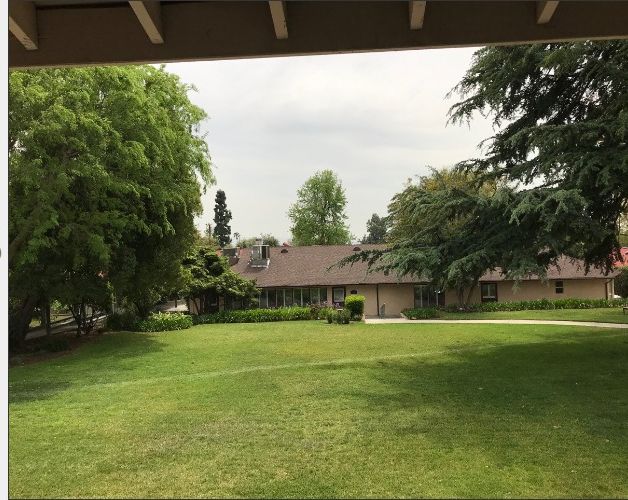 Grass, trees, and plants surround the British-style villa in the senior living community in California.