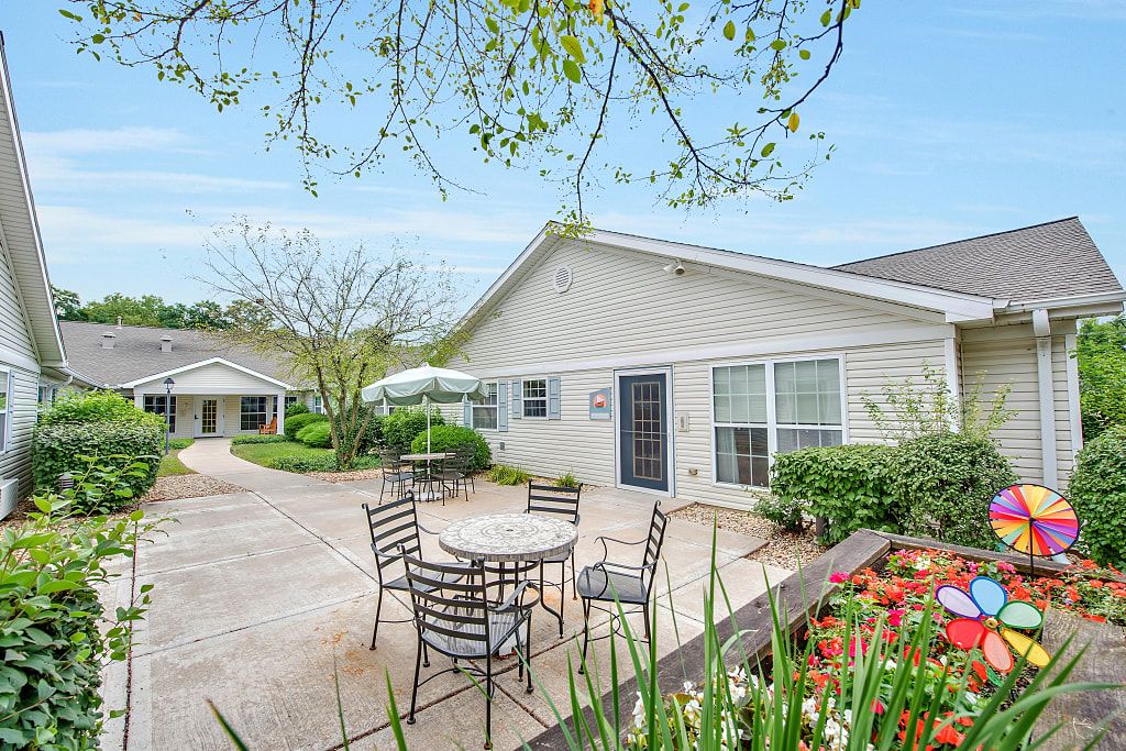 Suburban Charter Senior Living of Hazel Crest building with patio furniture in a lush backyard.