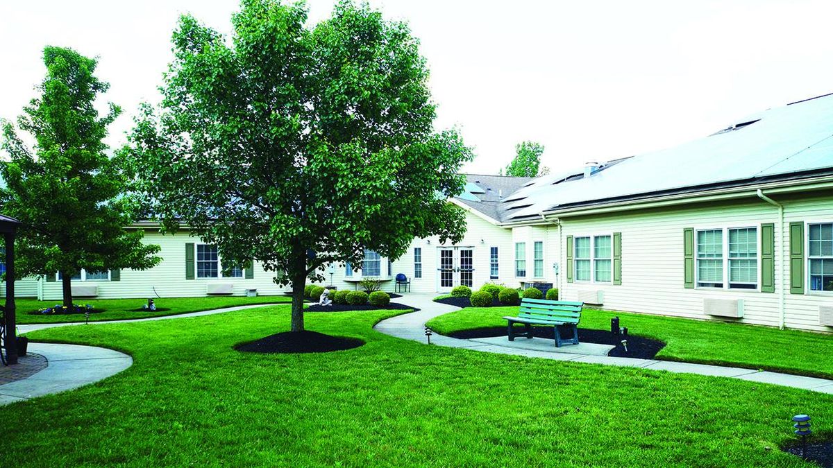 Greenfield Senior Living at Cross Keys featuring lush lawns, park scenery, and modern architecture.