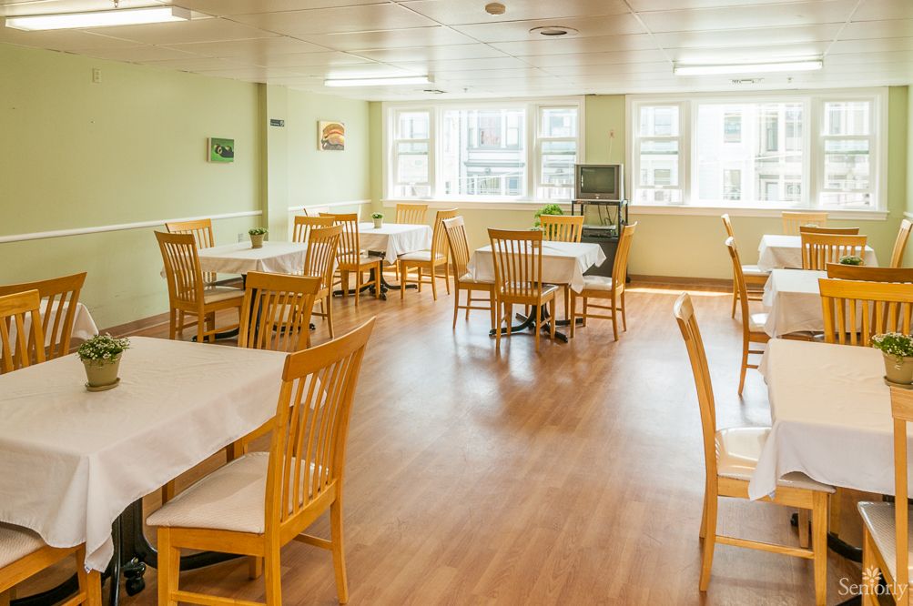 Victorian Manor senior living community interior featuring a hardwood floored cafeteria with furniture.