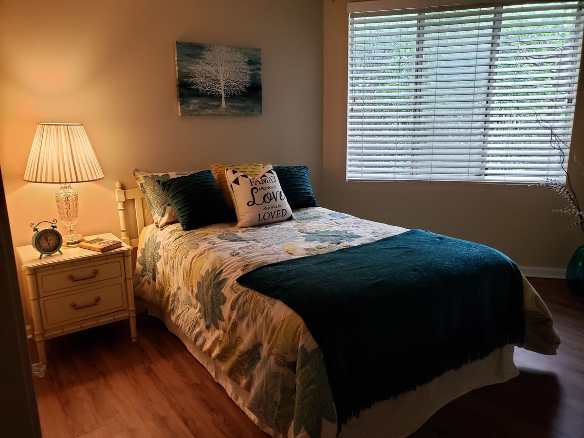 Interior design of a bedroom at The Pointe at Eastgate senior living community with hardwood flooring.