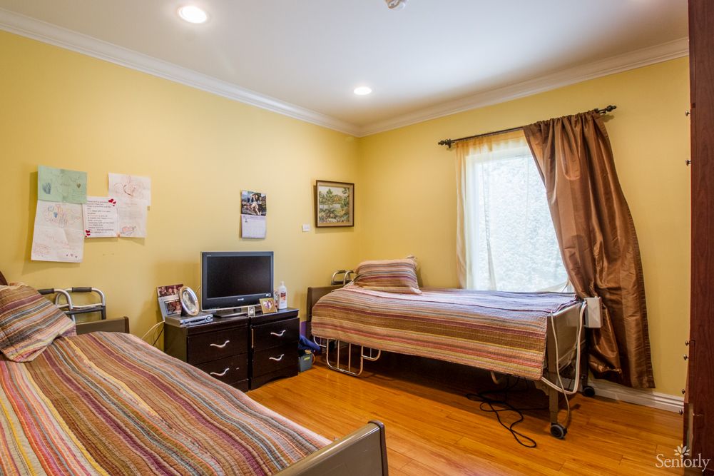 Senior living community bedroom with modern furniture, electronics, and hardwood flooring.