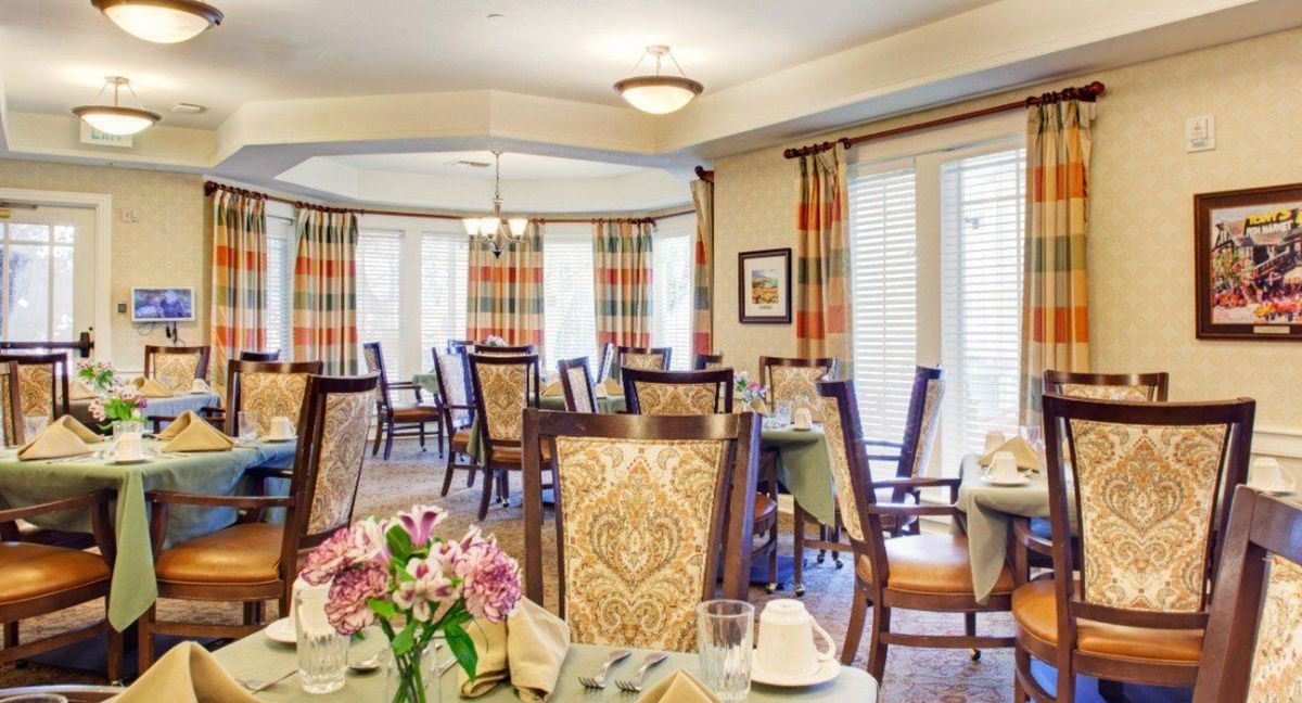 Senior living community dining room in Hermosa Beach with elegant furniture and flower decor.