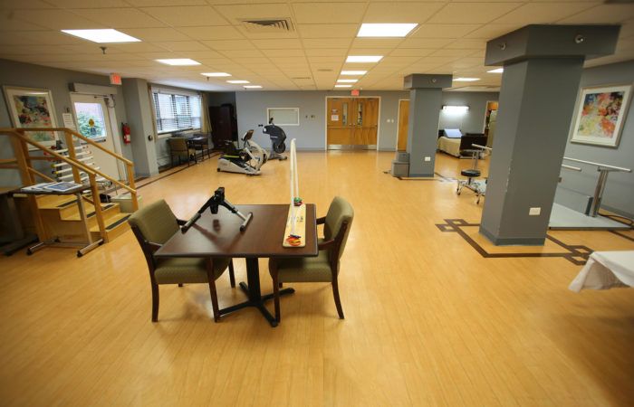 Senior living community interior with wooden furniture, gym facilities, and hospital wing.