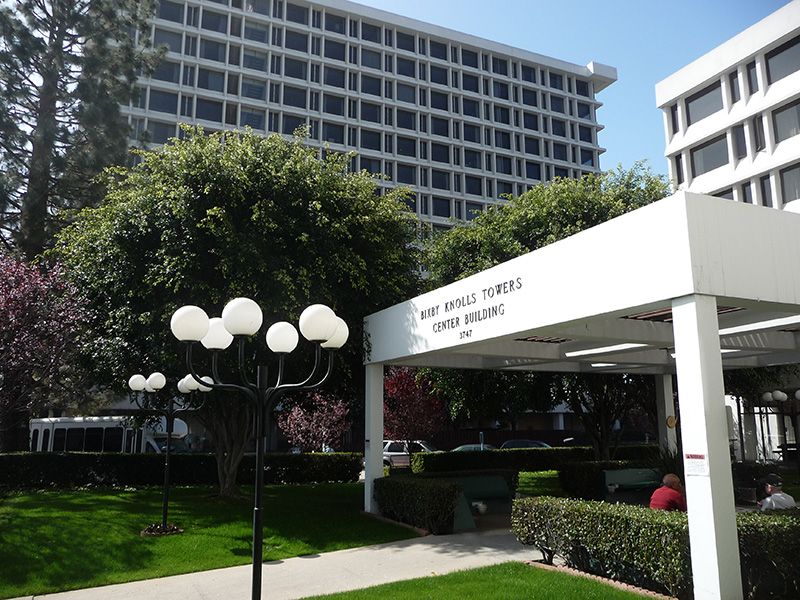 Senior living community, Bixby Knolls Tower, featuring lush gardens, patios, and urban architecture.