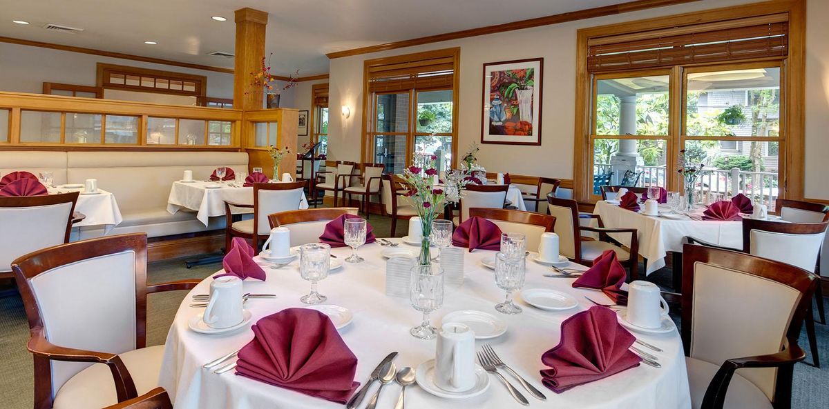 Senior living community dining room at North West Place with tables, chairs, and coffee cups.