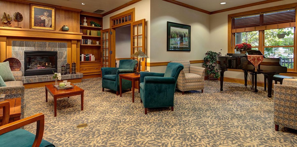 Senior living community interior with elegant decor, fireplace, piano, and residents.