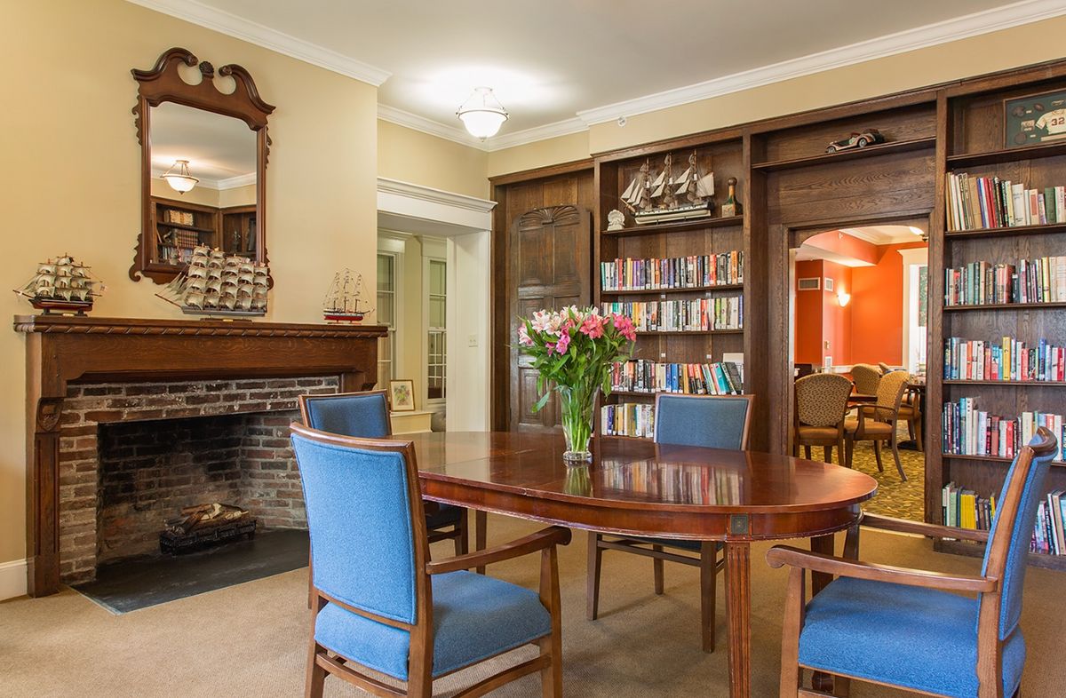 Senior living community interior at Paine Estate featuring a dining room, library, and fireplace.