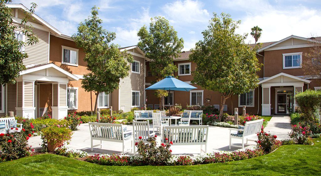 Senior living community, Raincross at Riverside, featuring lush greenery, benches, and modern architecture.