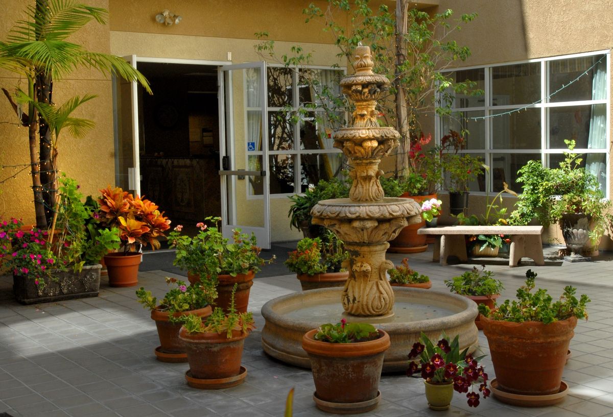 Senior living facility, Harbor Terrace Retirement Center of San Pedro, featuring indoor garden with potted plants and furniture.