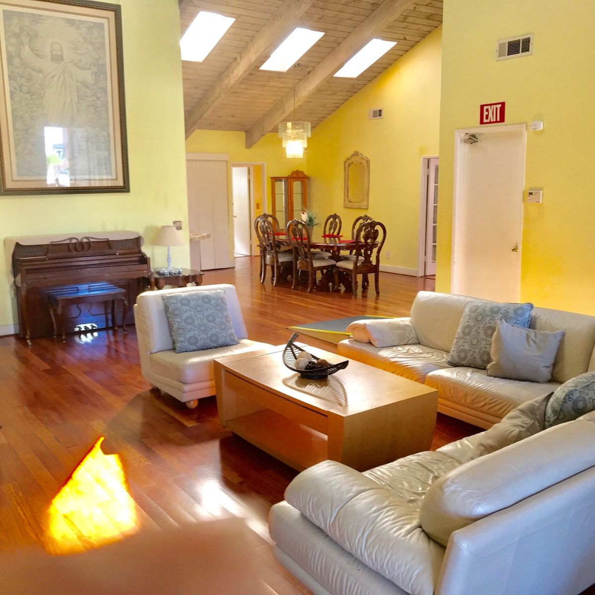 Elderly person in a cozy, well-furnished senior living room with piano, fireplace and dining area.