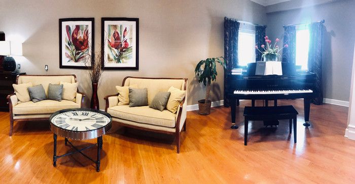 Interior of Crimson Village senior living room with hardwood flooring, piano, and decor.