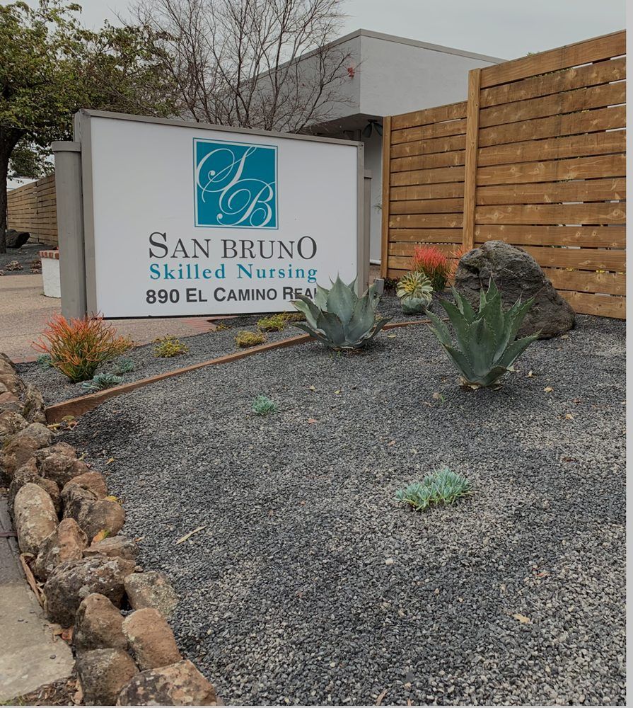 Outdoors view of San Bruno Skilled Nursing senior living community with lush vegetation.