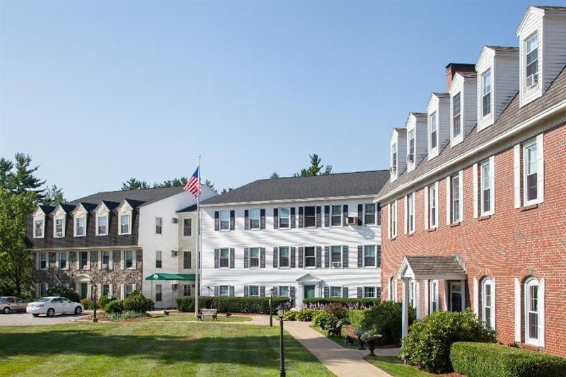 Senior living community, Langdon Place of Exeter, featuring condos, park bench, flag, and pet dog.