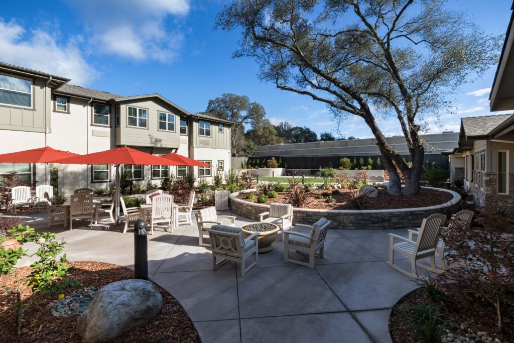 Backyard view of CountryHouse at Granite Bay senior living community with patio furniture and lush greenery.