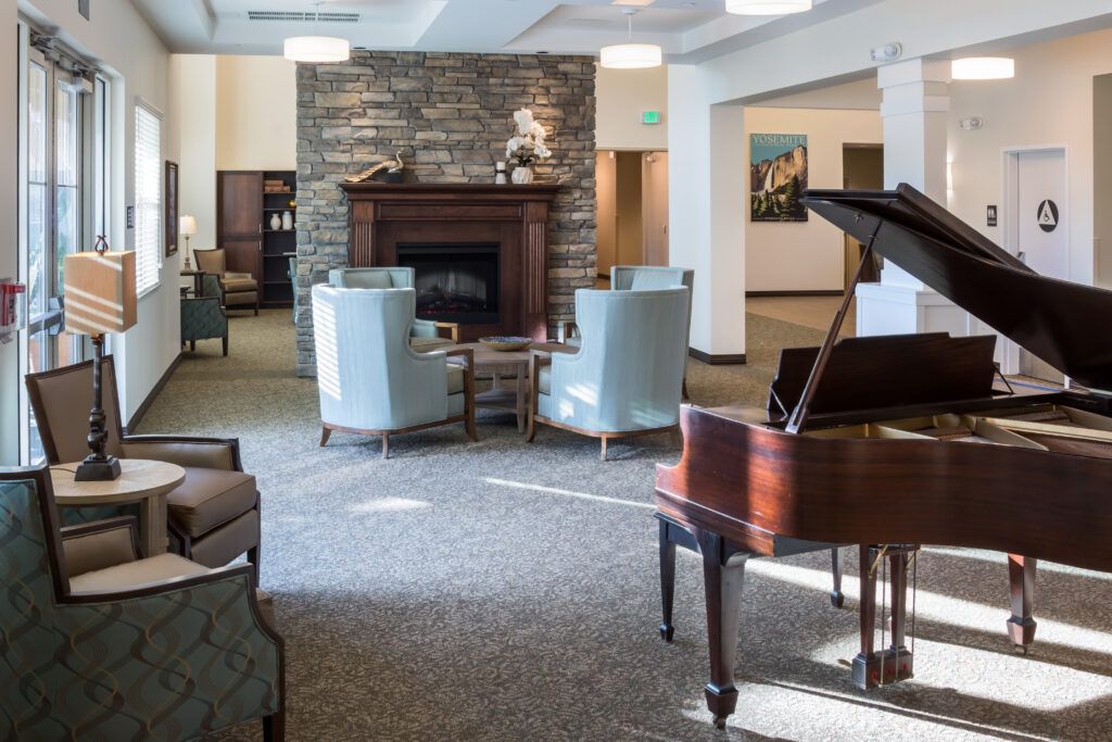 Interior view of CountryHouse at Granite Bay senior living community featuring grand piano and fireplace.