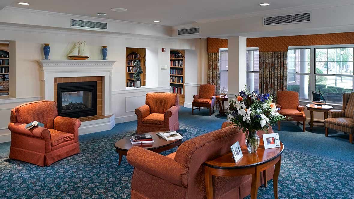 Senior living room at Atria Marina Place with cozy fireplace, elegant furniture and architecture.