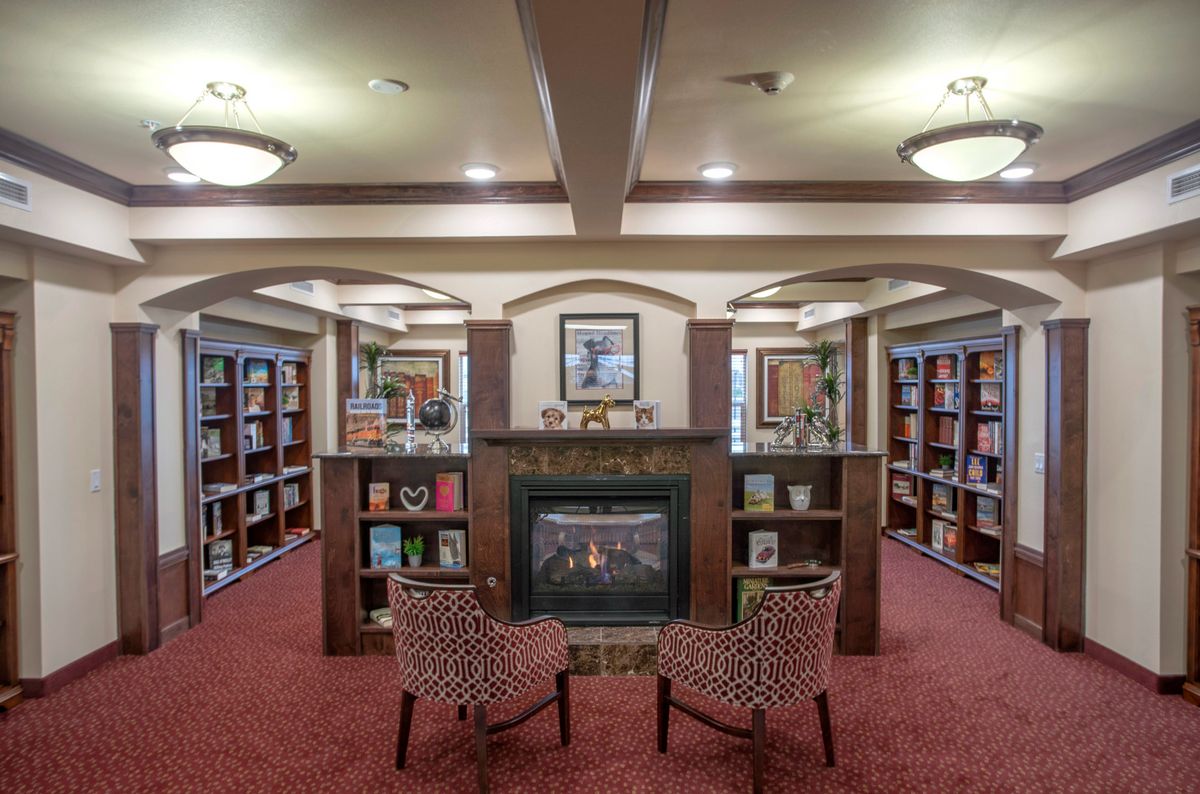 Senior enjoying a book in the elegantly designed library at Maple Ridge Gracious Retirement Living.