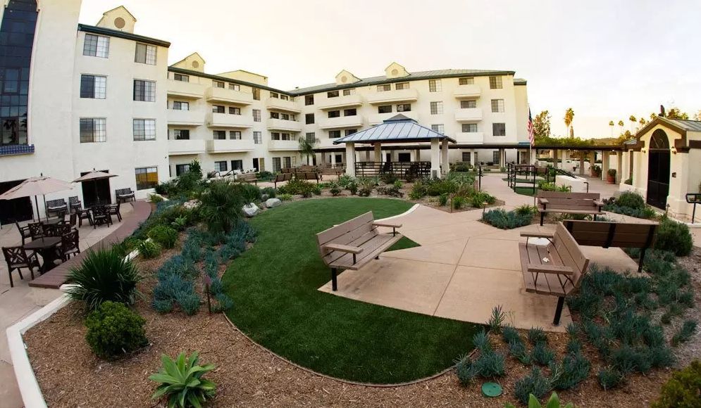 Outdoors view of Westmont Town Court, a senior living community with lush greenery and architectural buildings.